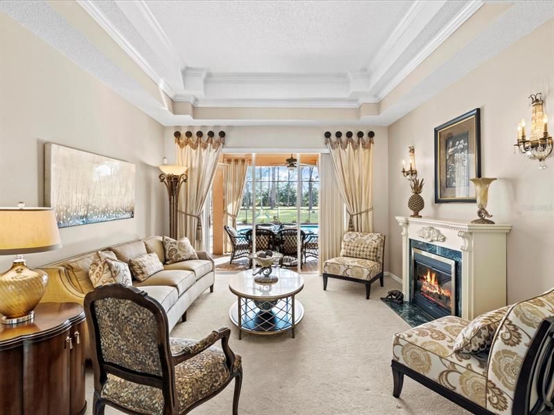 View from the Foyer into the Living Room w/ Coffered Ceilings & Beautiful View of the Pool/Backyard Area w/ Pocketing Sliding Glass Doors