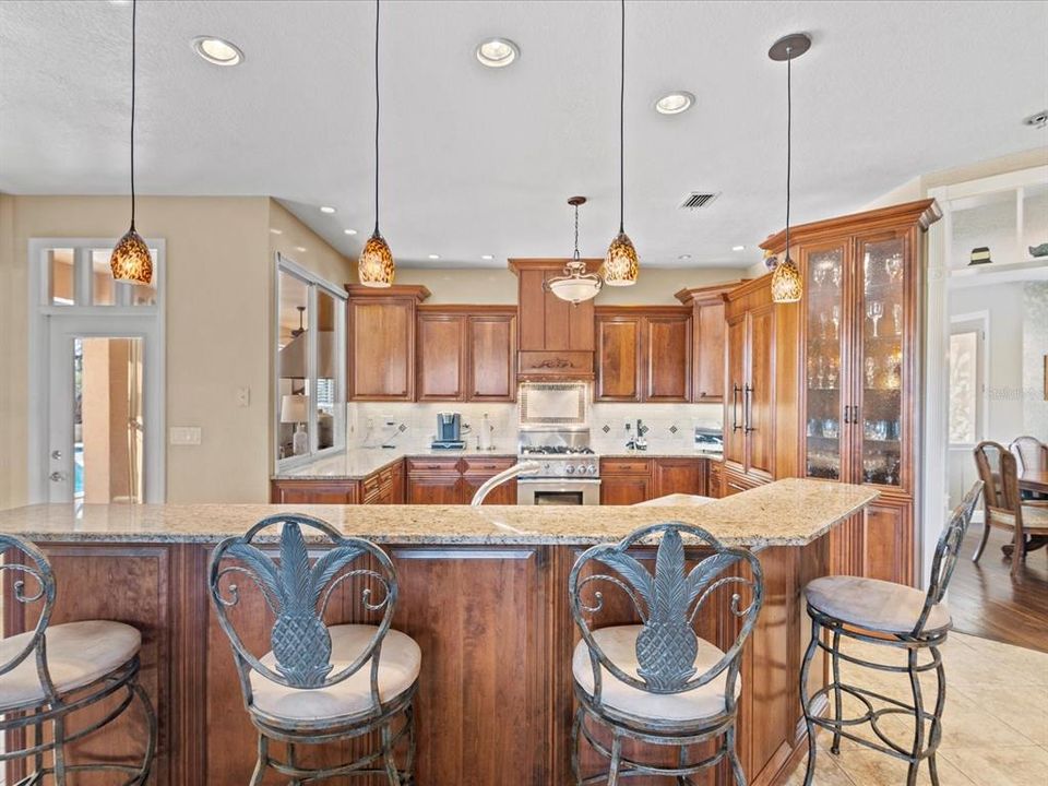 View from the Connected Family Room Looking into the Kitchen Highlighting the Large Island with Plenty of Space for Guests to Hangout & Eat at w/ Pendant Lighting