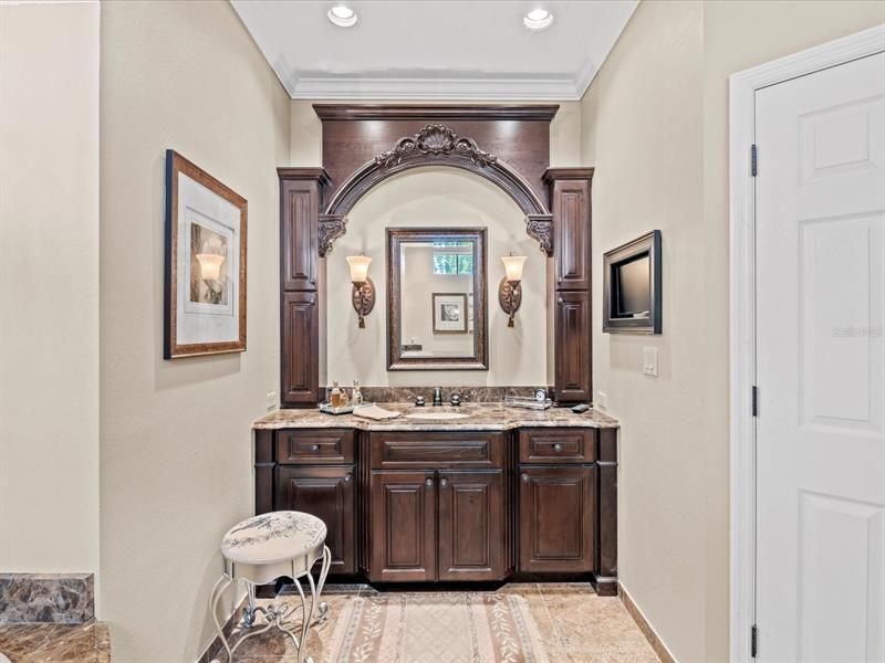 Close up of the Custom Made Cherry Wood Vanity Cabinets & Mirror Casement, Upper Side Cabinets w/ Sconce Style Lighting & TV on the Right Wall