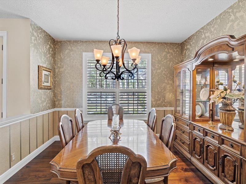 Formal Dining Area w/ Chandelier, Wood Flooring, Tall Baseboards, Chair Rail, Plantation Style Window Shutters, & Lots of Natural Light