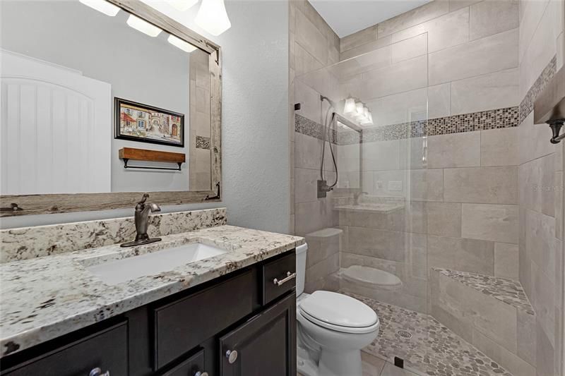 Hall Bath with great walk in shower with built in sitting bench. Granite Countertop and Custom mirror