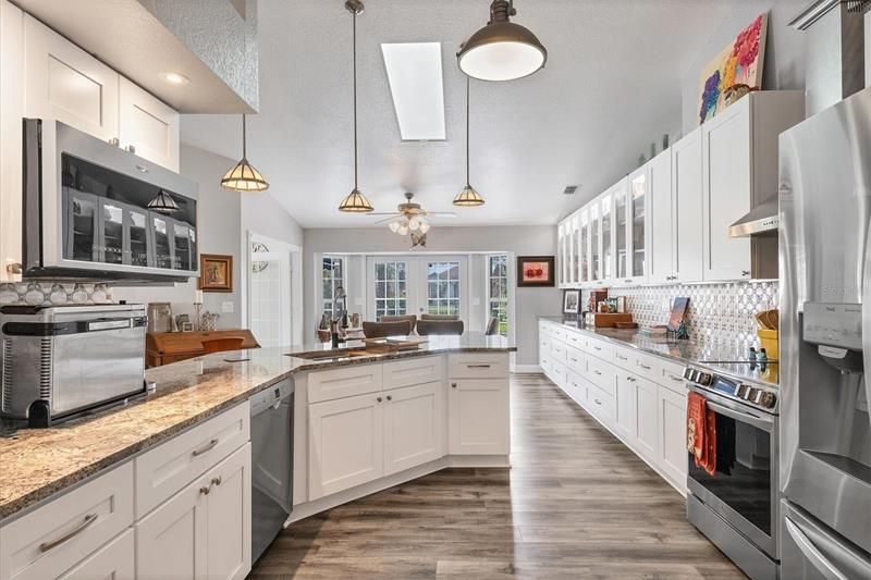 Lovely kitchen with cabinets galore overlooking eating area, pool and gardens.