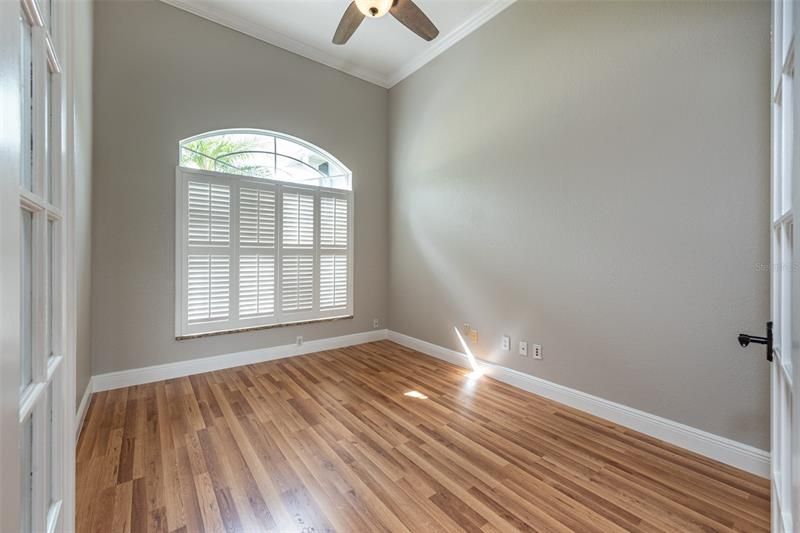 Office with ceiling fan, crown molding and shutters.
