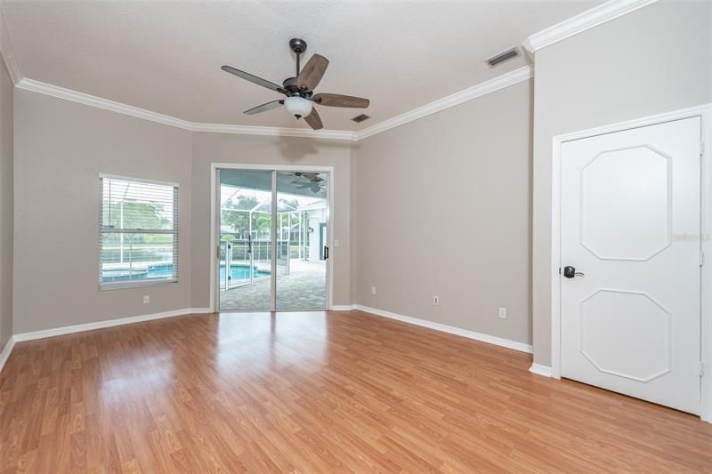 Master bedroom features crown molding, 2 walk-in closets and ceiling fan with sliders out to the pool area.