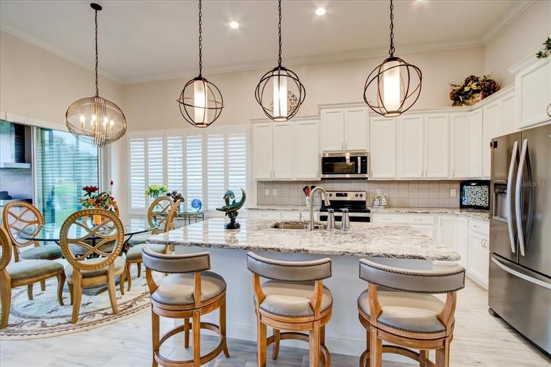 Stunning kitchen with designer lights, white cabinets and granite countertops.