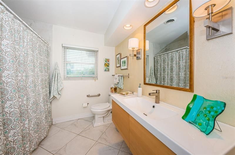 Full modern bath with floating vanity and deep soaking tub and shower.