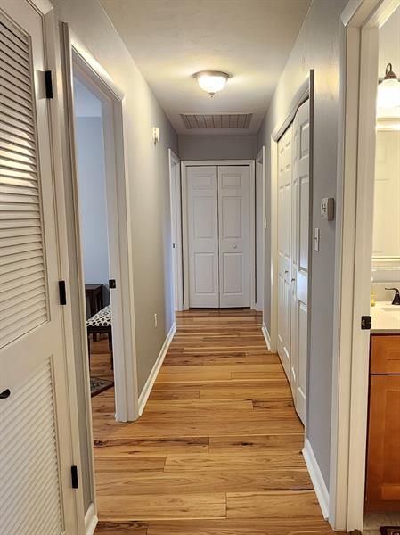 Hall with laundry closet to the right and linen closet at the end. Whole house exhaust fan can be seen in the ceiling.