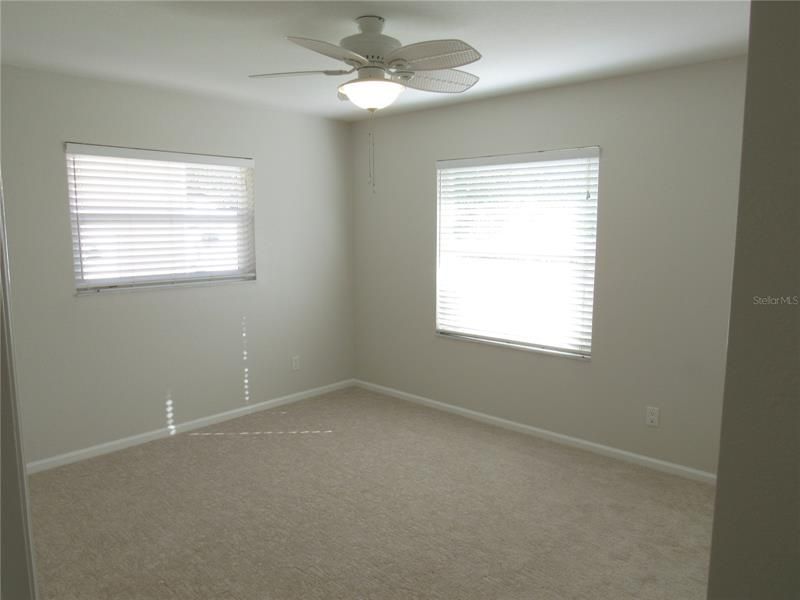 Front bedroom with t windows and ceiling fan