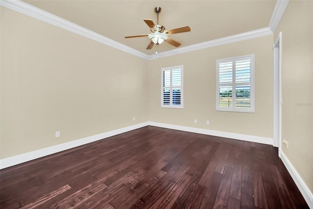 Guest Bedroom with huge walk-in custom closet, fan, plantation shutters, hardwood floors and crown molding