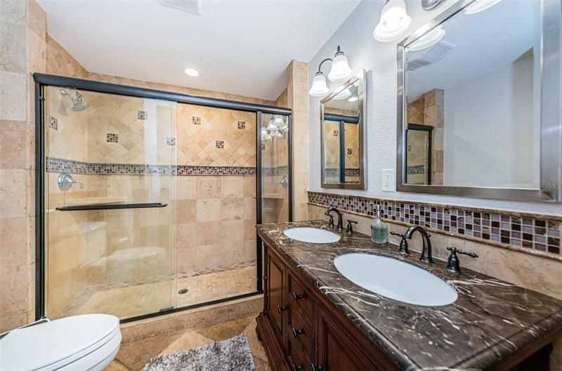 Adjacent bathroom with dual sinks and marble counter. Dual head walk-in shower.