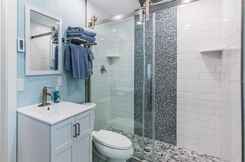 Guest bathroom with walk-in shower and designer tile finishes. Convenient access to the pool!
