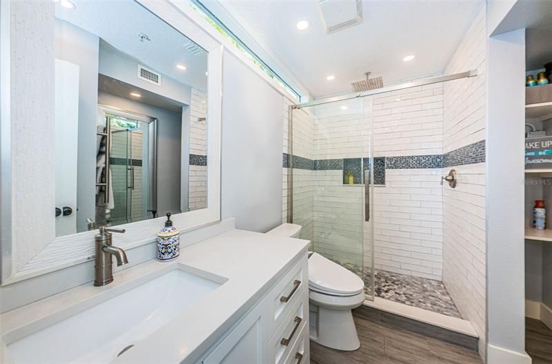 Adjacent bathroom with walk-in shower, rainfall showerhead, and tiled inset.