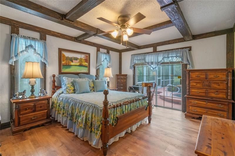 Master bedroom with wood beam ceilings and Oak Hardwood Floors. Slider leads out to enclosed pool area.