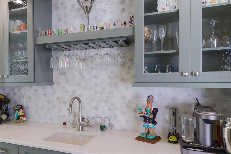 The wet bar has a sink, wine fridge and custom lighted cabinetry.