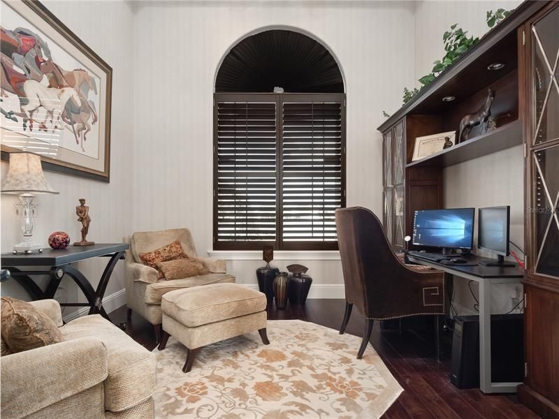 The dedicated office located at the front right of the home has wood flooring, newly added wooden beams, shutters and luxe wallpaper.