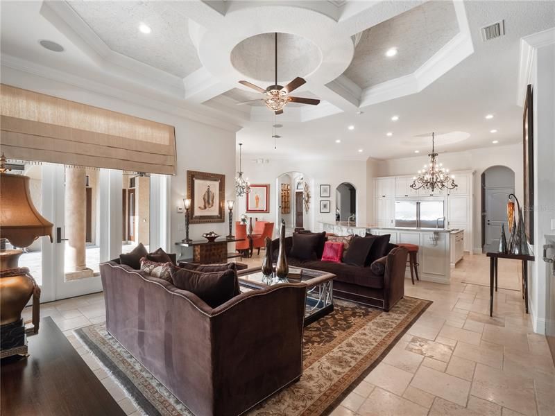 The fabulous family room boasts a detailed ceiling and custom built-in that surrounds the TV with elegant glass display shelves and plenty of cabinet storage.