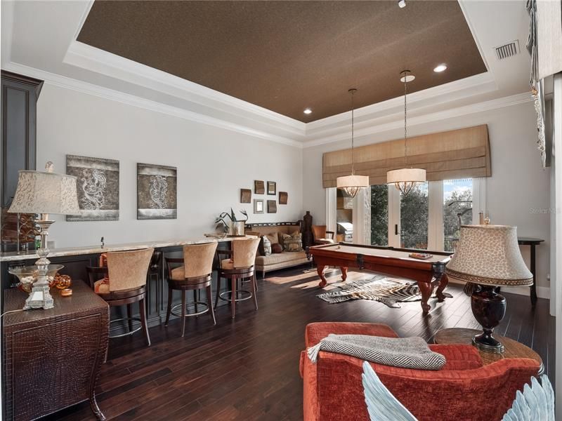 Transition to the gorgeous game room , complete with a with views of the lake, fabulous bar that boasts a refrigerator, ice maker and dishwasher.