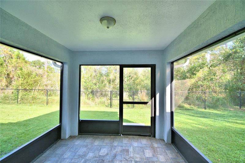 Screened in patio with pleasant view of well-manicured lawn.