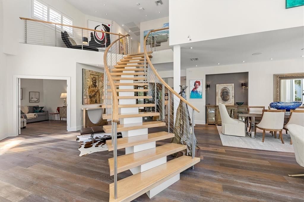 Between the stately foyer and the main living space, a magnificent floating staircase lends architectural grandeur with European white oak planks and a stainless steel railing