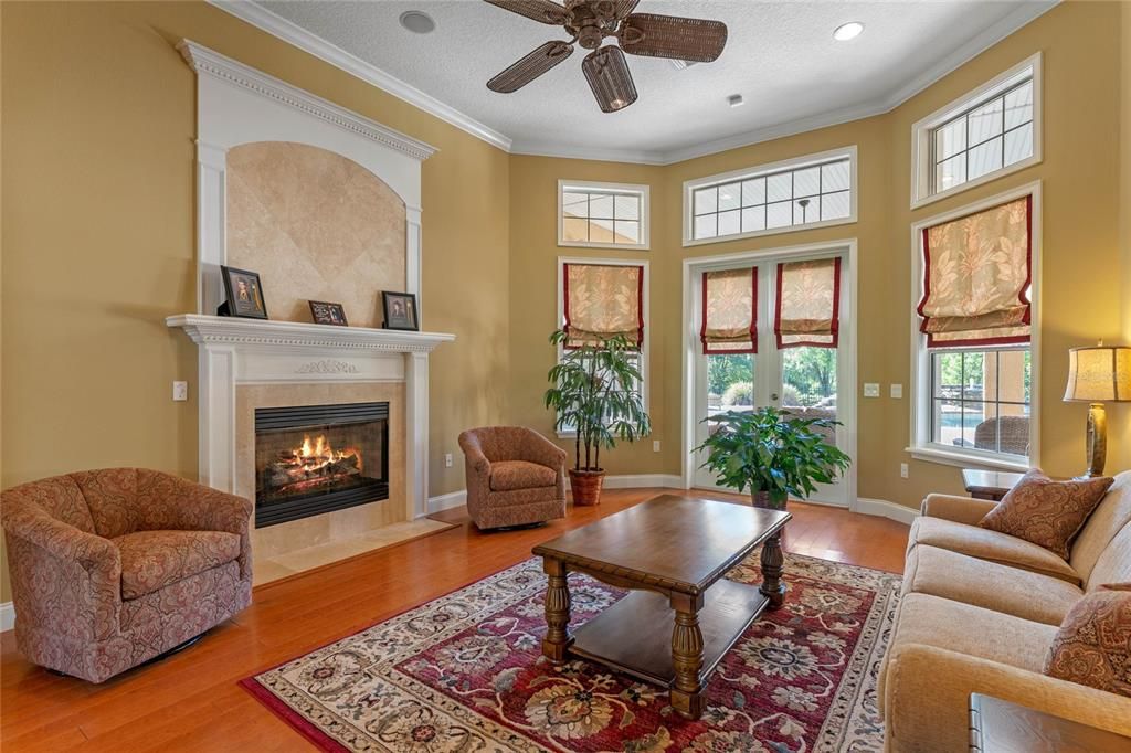 Formal living room with gas fireplace and French doors leading to the pool and lanai.