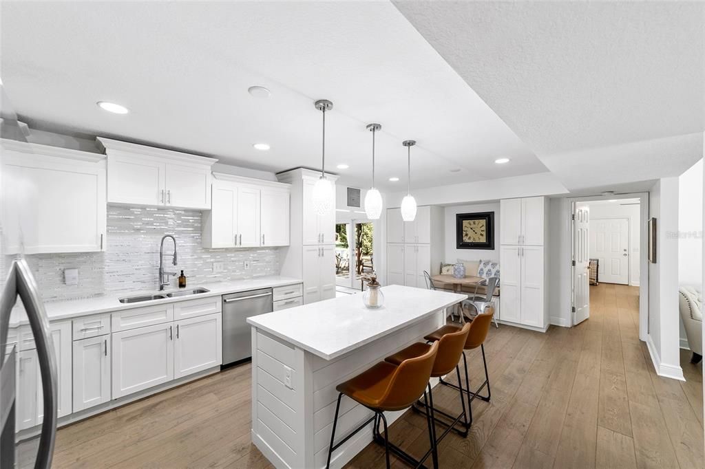 Open and airy eat-in kitchen featuring quartz countertops, pendant lighting, stainless steel appliances, and spacious kitchen island.