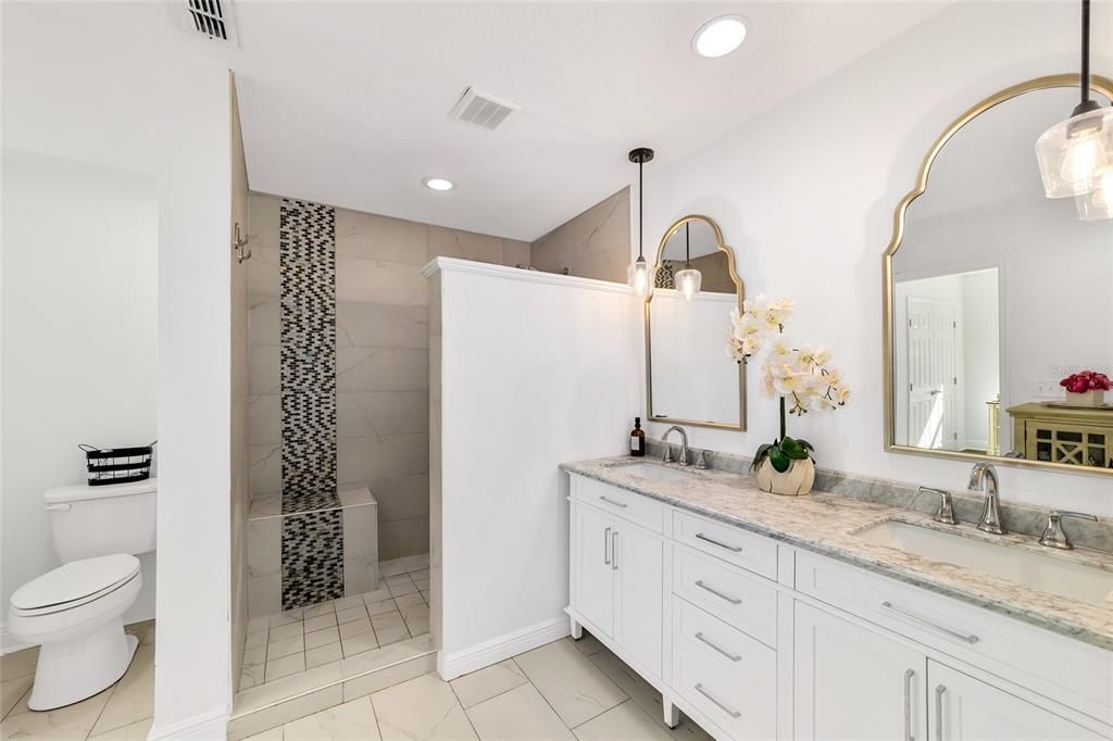 Primary suite with double vanity, desirable fixtures, and walk in shower.