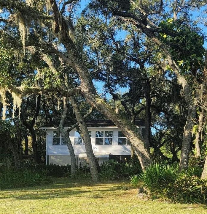 Exterior front of house overlooking the lake surrounded by the beautiful Florida friendly landscape. Perfect spot for a swing!