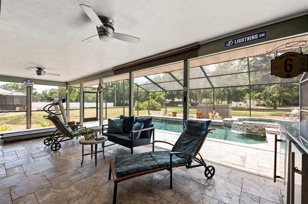 Lanai with Travertine Tile flooring-covered area for relaxing, eating or just enjoying in the rain-outdoor Kitchen to the right-Grill,Refrig and Kegerator for outdoor fun!