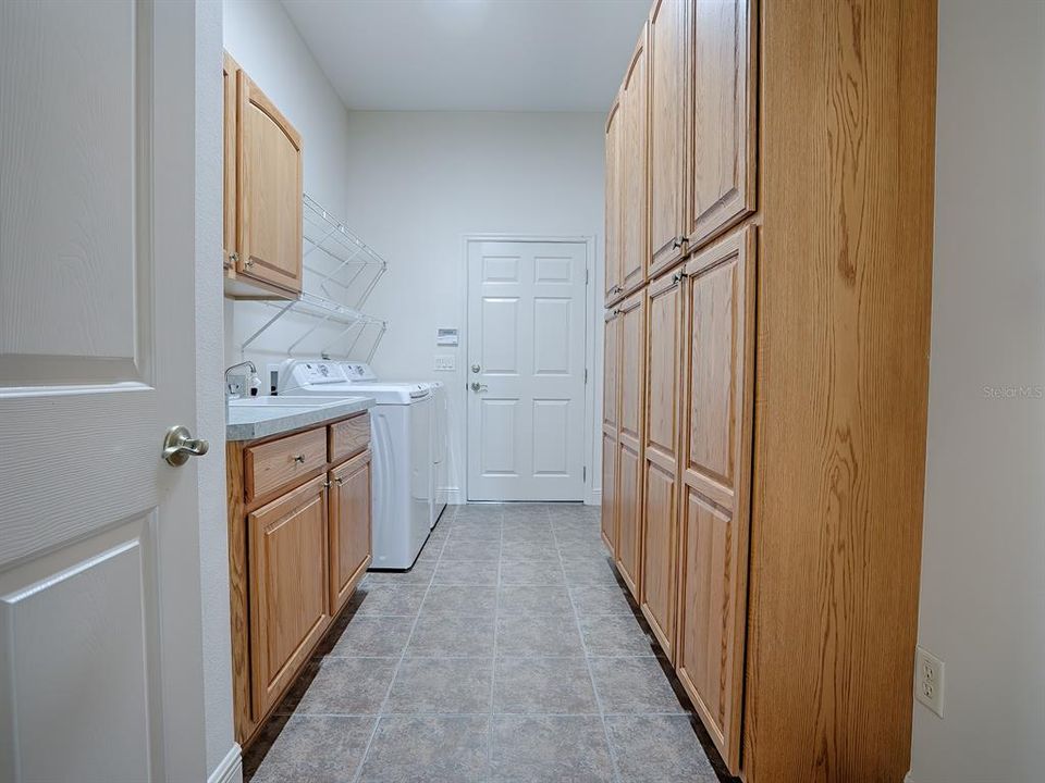 SPACIOUS LAUNDRY ROOM OFF THE KITCHEN AREA WITH LOTS OF EXTRA STORAGE CABINETS AND A BUILT-IN SINK.  THE DOOR IN THE BACK LEADS TO THE GARAGE.