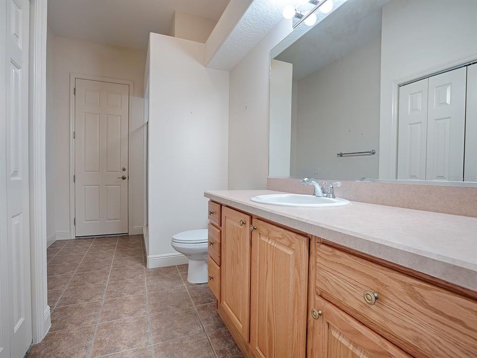 3RD BATH ACROSS FROM THE GUEST ROOM WITH BEVELED EDGE COUNTER, LARGE LINEN CLOSET AND TILED SHOWER.  THIS IS CALLED THE "POOL BATH" AS THE DOOR IN THE BACK OPENS TO THE LANAI AND SHOULD YOU HAVE A POOL, EASILY ACCESSIBLE.