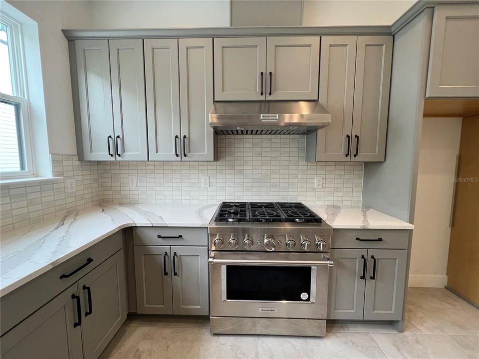 Gourmet kitchen with natural gas stove, vented hood, quartz countertops, upgraded cabinetry, Kohler plumbing fixtures and more!