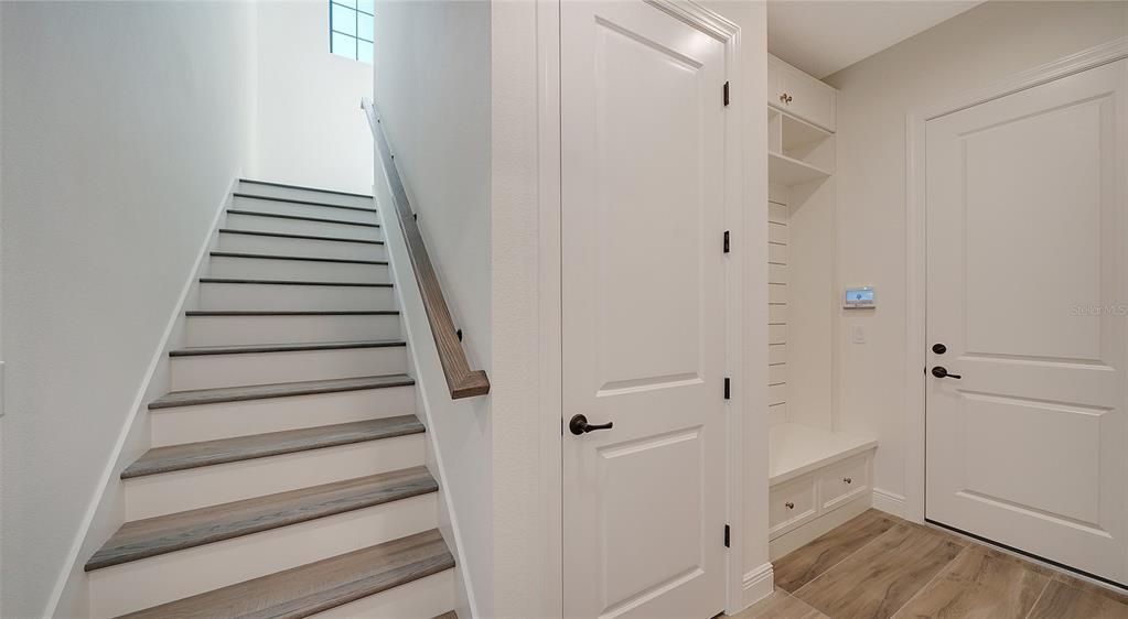 Stairs and garage entry with storage