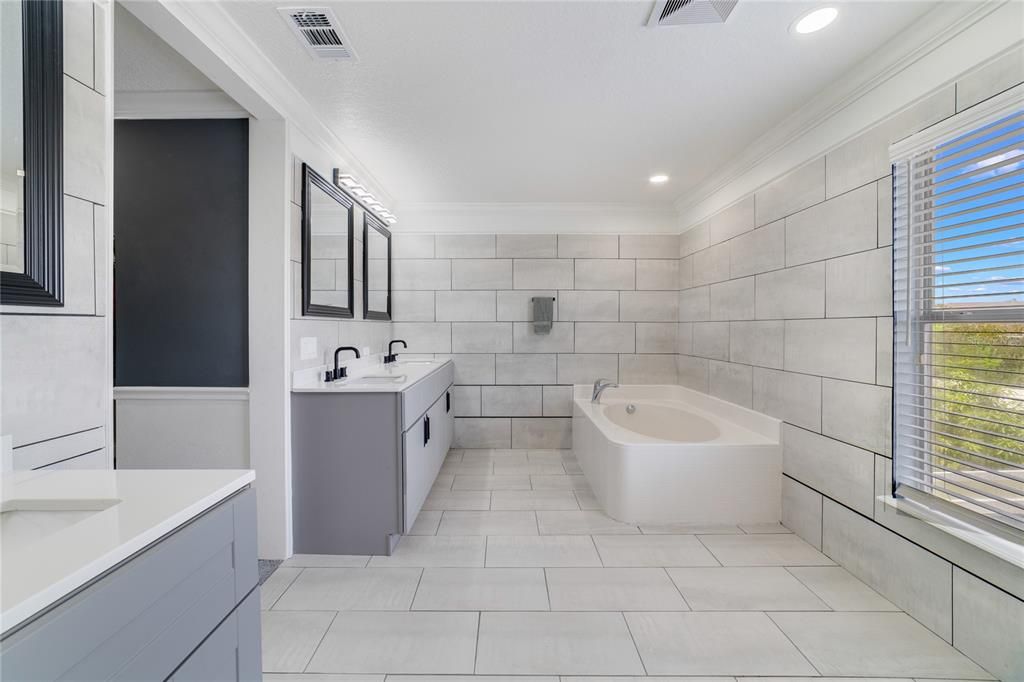 Your en-suite bath filled with custom tile work, split vanities, soaking tub, separate shower and a window for great natural light!