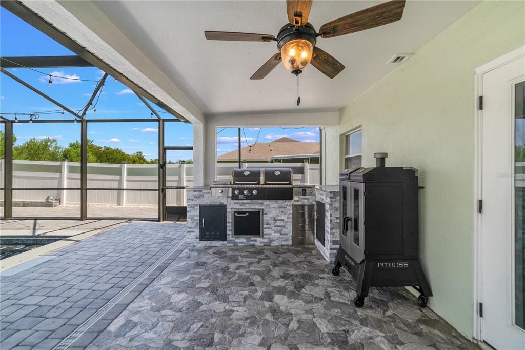 Fully screened for optimal comfort the paver patio and COVERED LANAI with SUMMER KITCHEN will make this the place all your friends and family want to hang out and your yard is FENCED for added privacy!