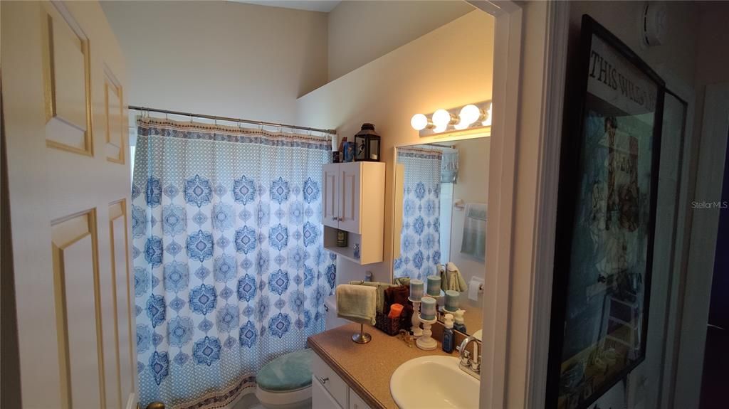 Hall bathroom has tub/shower, display shelf and a linen closet