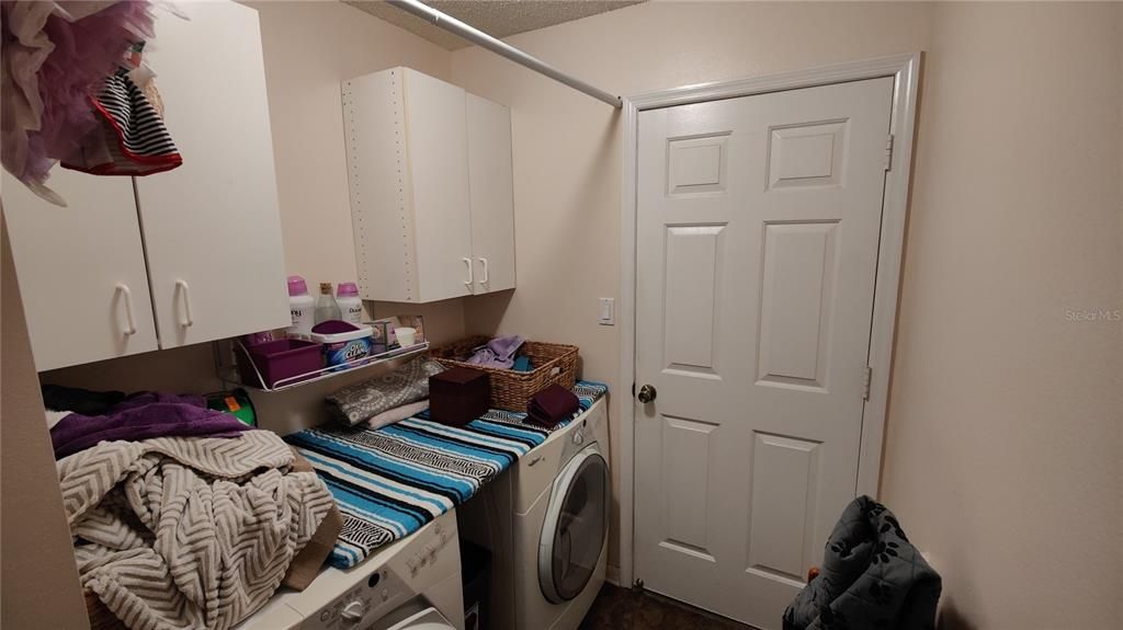 Inside Laundry has washer, dryer, storage cabinets and closet pole. Door exits to 2 car garage