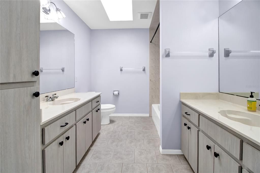 Upstairs bathroom showing separate double vanities, cabinet space galore and tub/shower combination