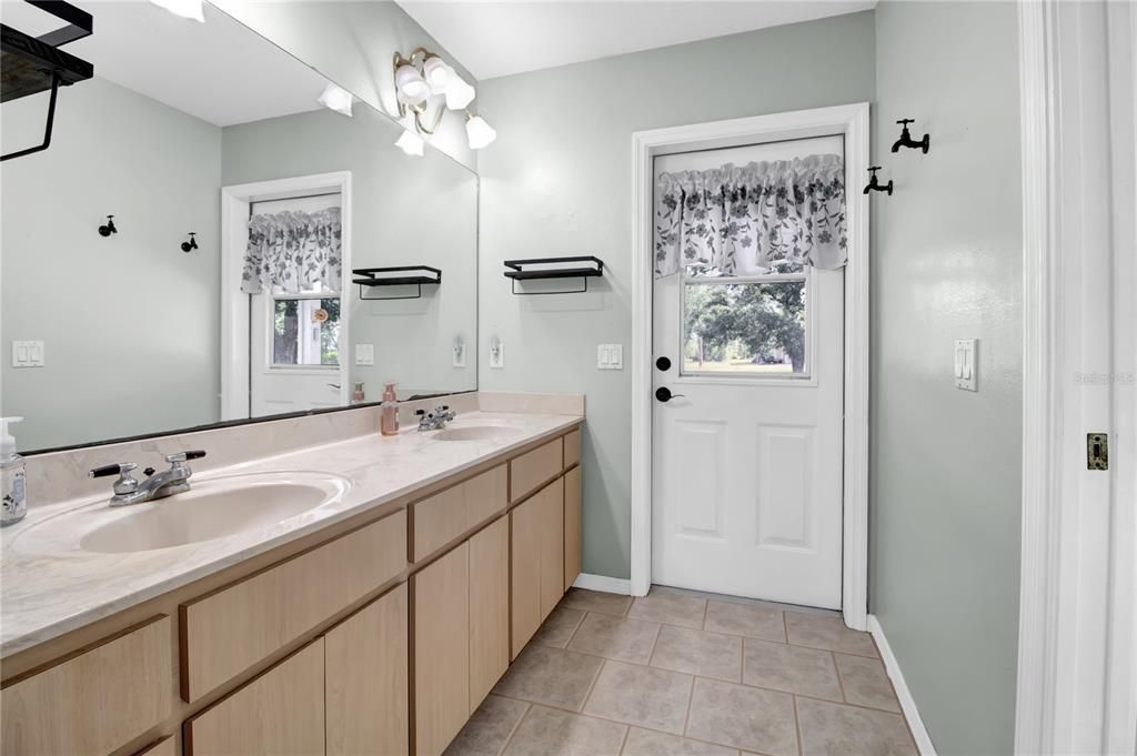 Master bathroom with double vanities, shower and toilet separated by door on right and DOOR out to PORCH (pool bath)