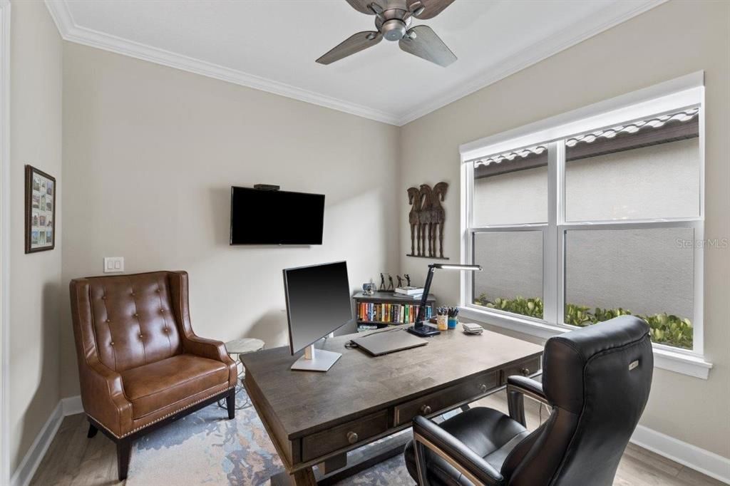 Den/Office featuring wood-look laminate flooring, double doors, and custom shades.