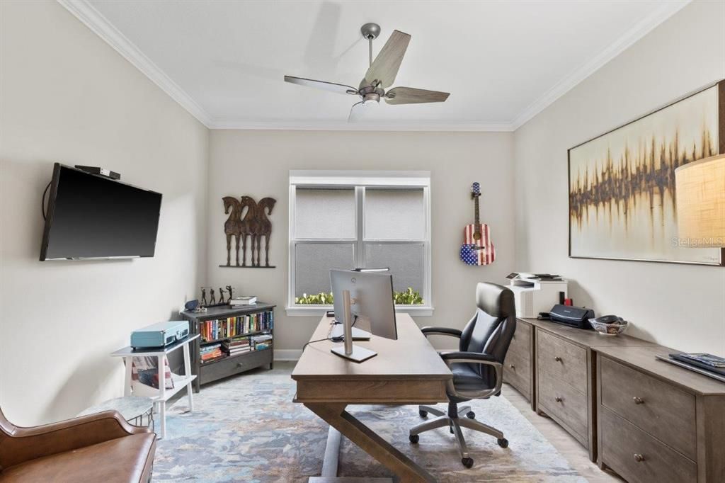 Den/Office featuring wood-look laminate flooring, double doors, and custom shades.