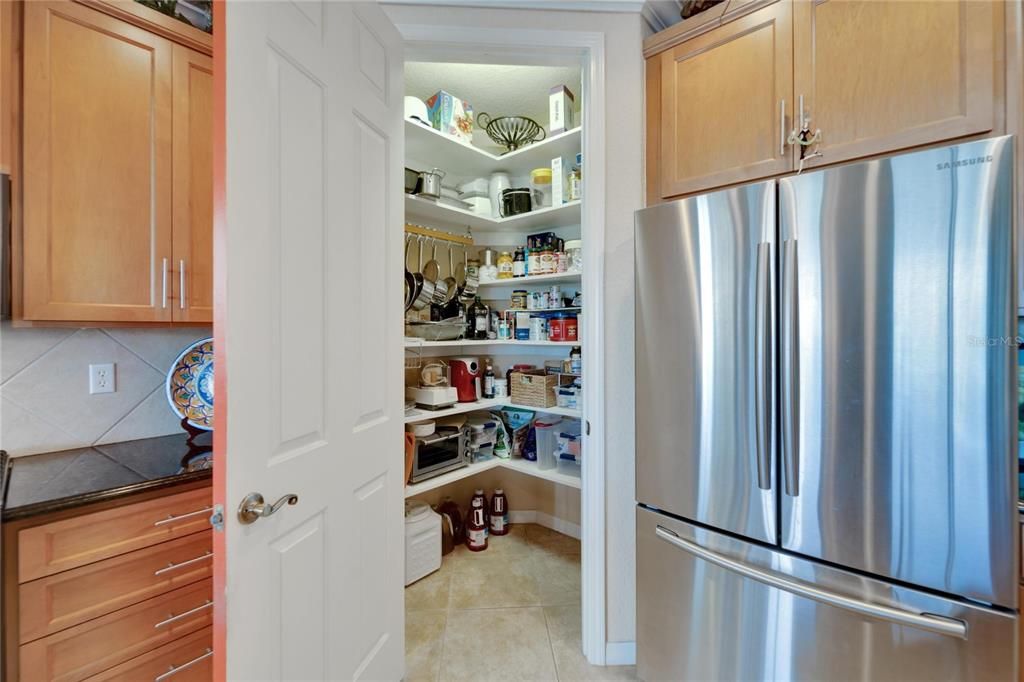 Lighted spacious walk in pantry with custom shelving.