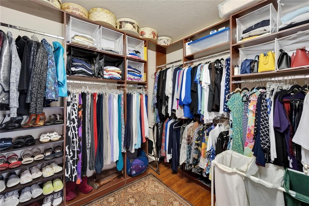 Very large spacious corner style walk-in closet with custom California Style shelving offers enough space for multiple occupants to utilize.