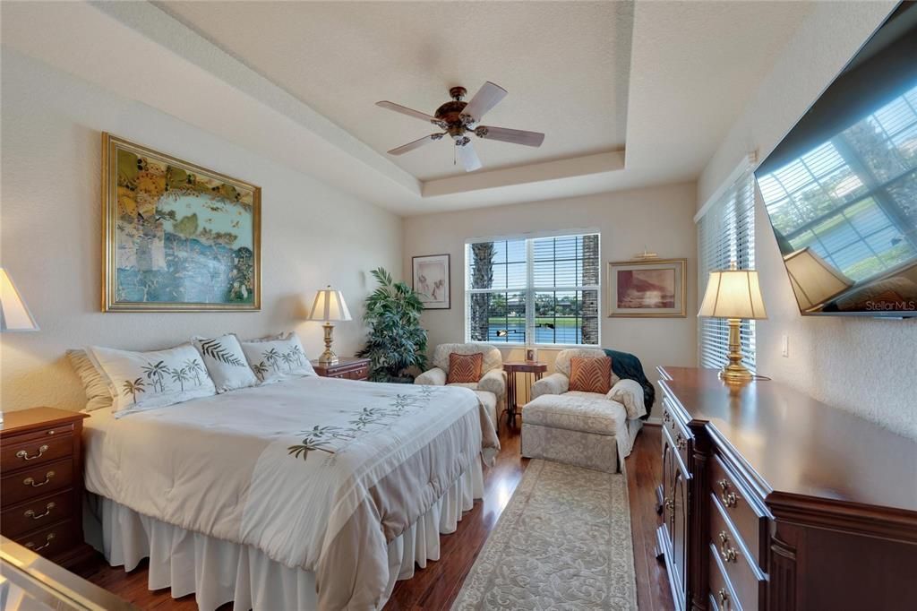 Primary ensuite bedroom offers beautiful architectural features incuding tray ceilings sliding doors and large windows for a stunning water view.