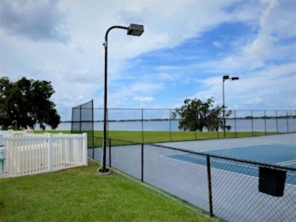 Tennis court with fenced in pool area to the left.