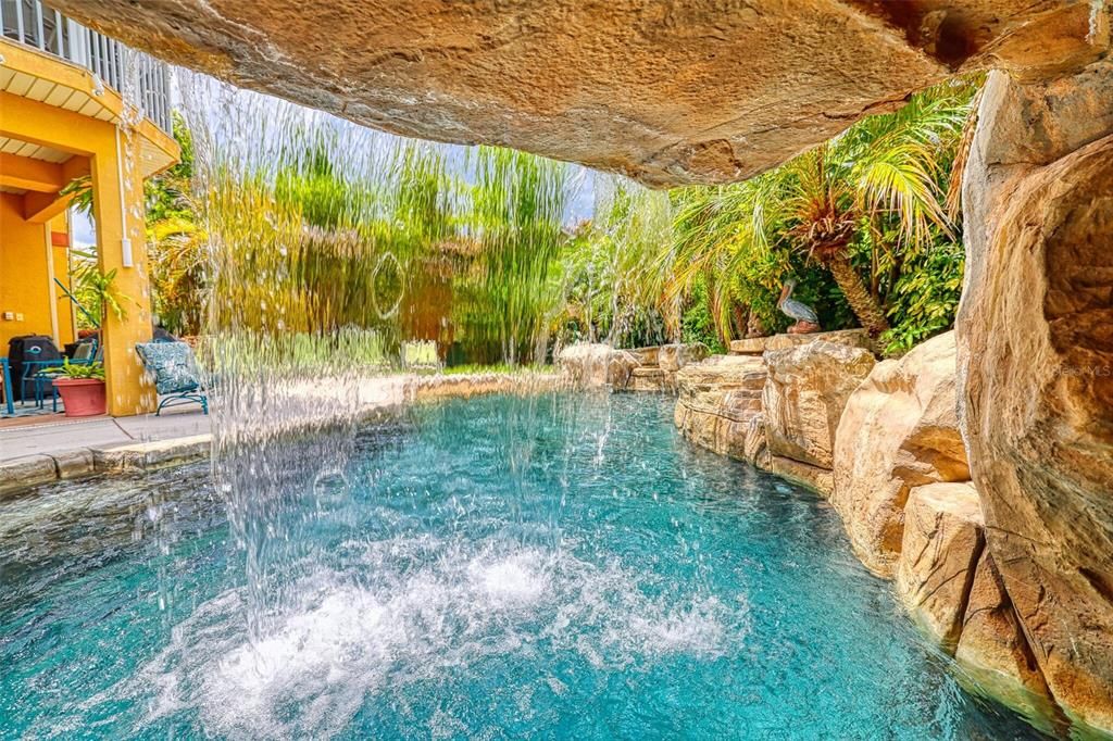 heated Saltwater Pool has a grotto, waterfall, custom hot tub, color changing lights, and outdoor shower.