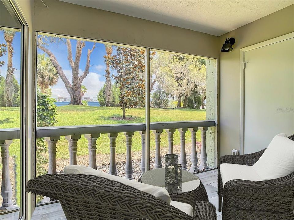 Virtually Staged- screened-in lanai adorned with complementary tile flooring. Savor a cup of coffee on breezy mornings or relax on tranquil afternoons or evenings as you unwind while relishing the picturesque views of the meticulously maintained grounds