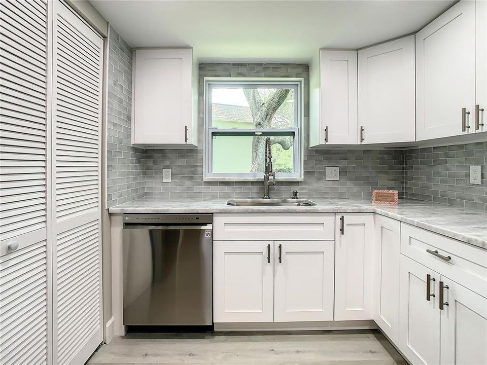The Well-equipped Kitchen with upgraded LG stainless-steel appliances, including a convection oven with air fryer, soft close cabinets, designer marble countertops extended for a convenient breakfast bar, a stylish glass tile backsplash, an upgraded Kohler faucet, can lighting, and a spacious pantry
