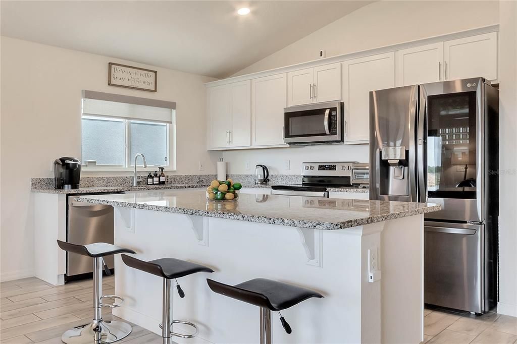 The heart of the home is the stunning kitchen, boasting upgraded white cabinetry with crown molding, granite countertops, and a counter height island that opens up to the dining room and living room.