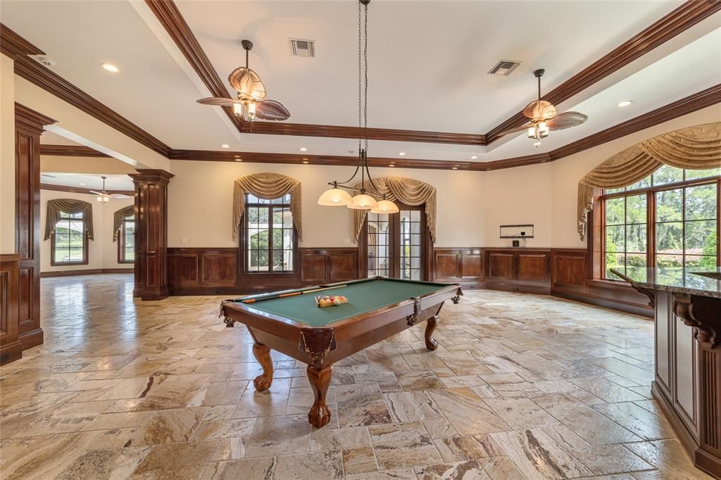 Billiard room with built in bar with beverage/wine refrigerator and opens to pool deck