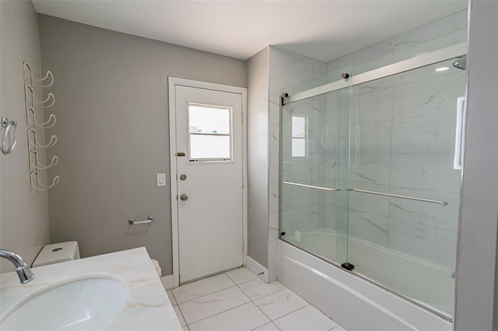 Upgraded guest bathroom with door leading to pool